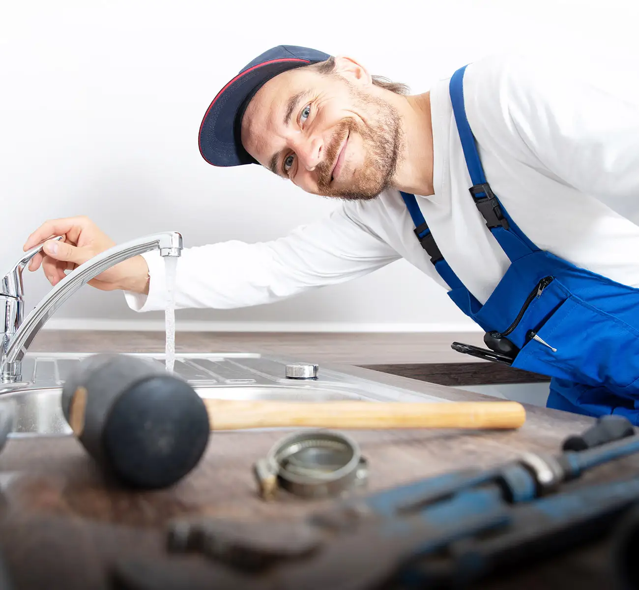 Klempner lächelt nach erfolgreicher Reparatur eines Wasserhahns